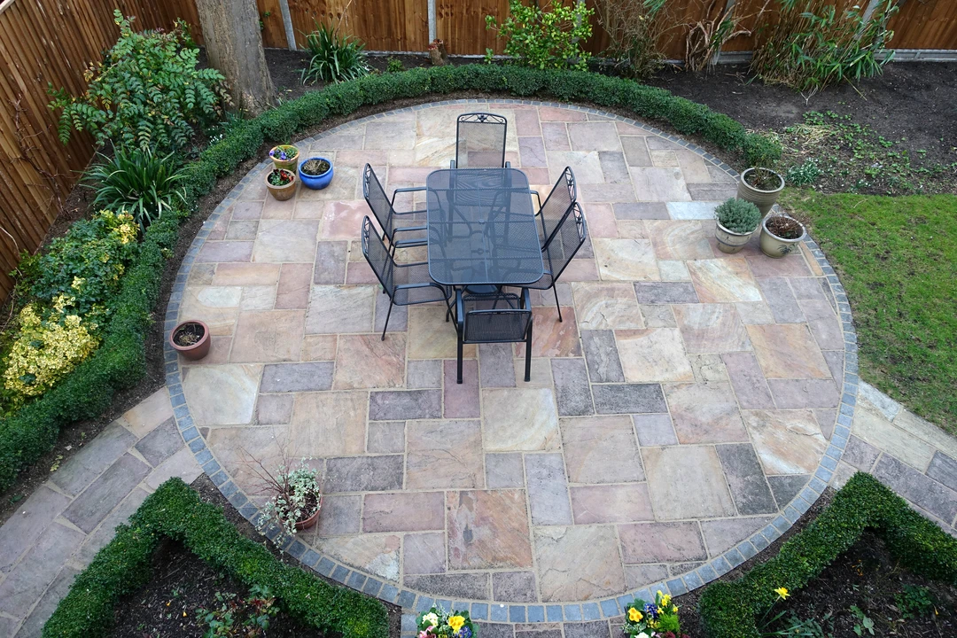 Evergreen Enterprises Hardscaping Potomac 1 - Evergreen Enterprises Circular stone patio with dining set bordered by greenery illustrating detailed hardscaping craftsmanship.