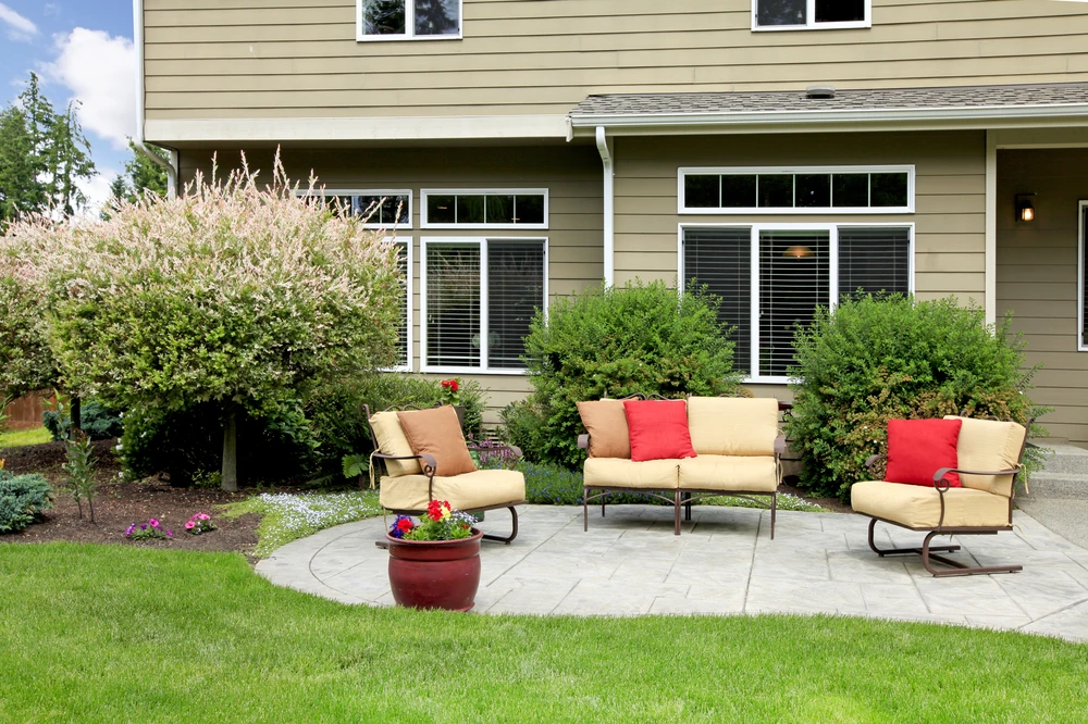 Backyard patio with cushioned seating, paver surface, and manicured lawn behind a Rockville, MD home.
