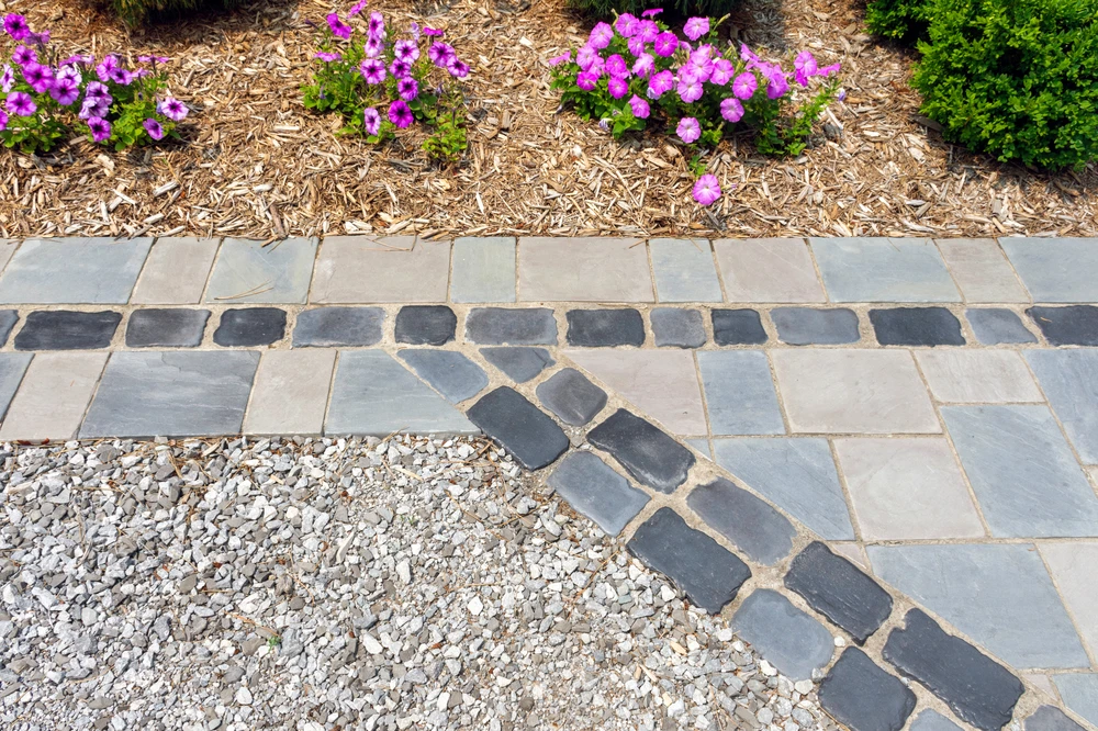 Detailed stone paver walkway with contrasting borders and flower beds showcasing hardscape craftsmanship in Rockville MD.