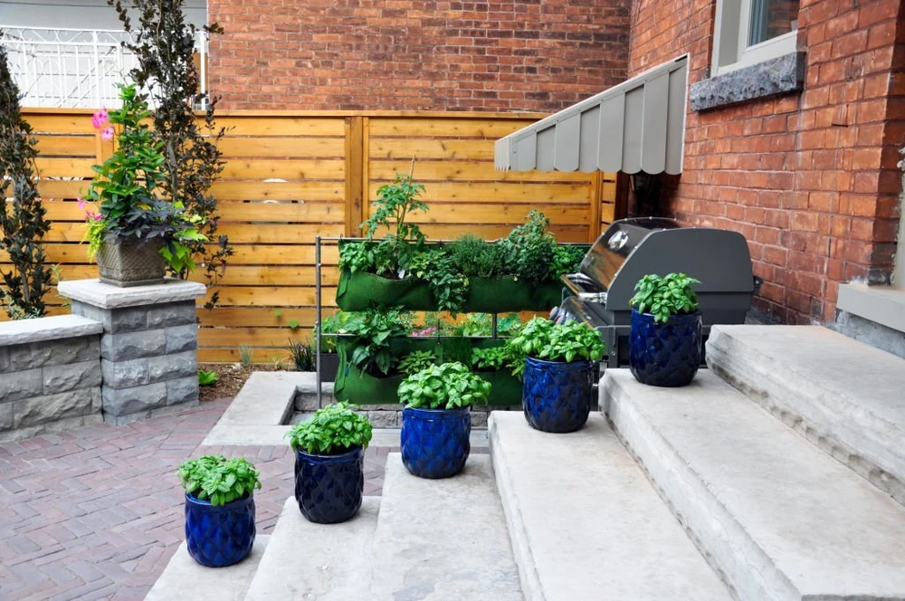 Small patio with brick masonry walls, built-in grill station, and tiered herb garden in blue ceramic pots.
