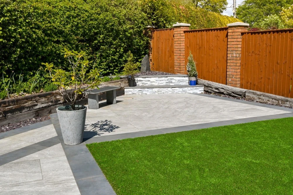 Modern concrete patio with built-in bench seating, planter, and wood privacy fence in a clean Rockville MD, backyard design.